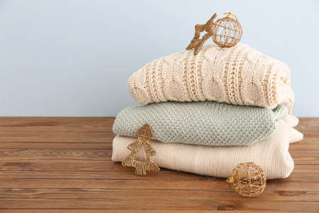 Stack of winter clothes with Christmas decor on wooden tableの写真素材
