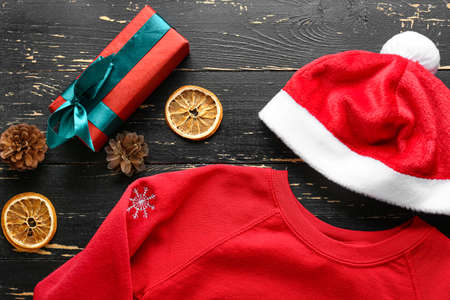 Christmas clothes with gift box and Santa Claus hat on wooden backgroundの写真素材
