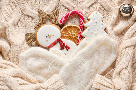 Christmas cookies with mittens on warm sweater, top view