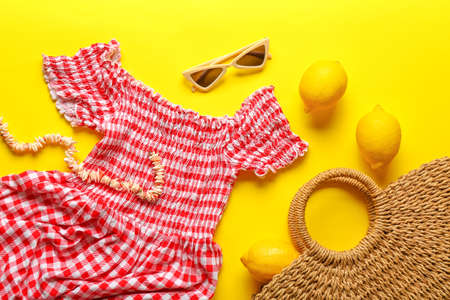 Summer composition with dress, bag and lemons on color background