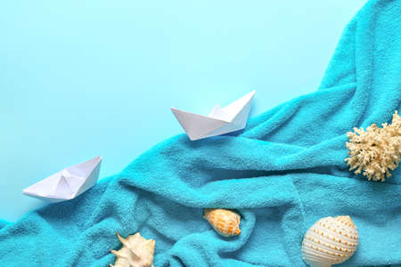 Summer composition with towel, paper boats and seashells on color backgroundの写真素材