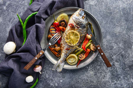 Plate with prepared dorado fish and vegetables on gray backgroundの写真素材