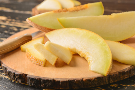 Tasty melon with knife on wooden boardの写真素材