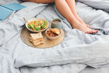 Woman with tasty breakfast sitting in bedの写真素材