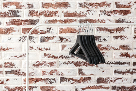 Rack with clothes hangers against brick wallの写真素材