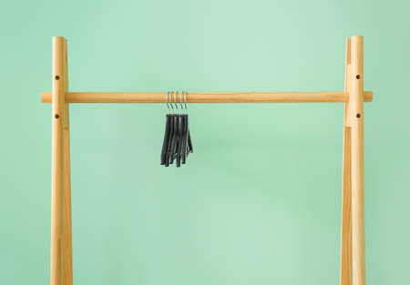 Rack with clothes hangers on color background
