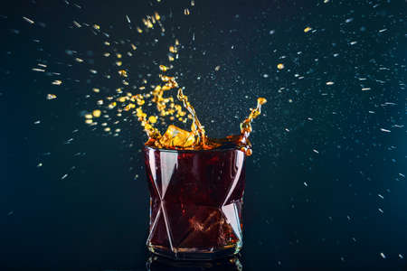 Glass of tasty cocktail with splash on dark backgroundの写真素材