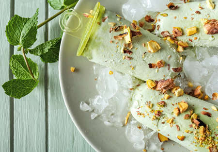 Plate with tasty pistachio ice cream on wooden table, closeup