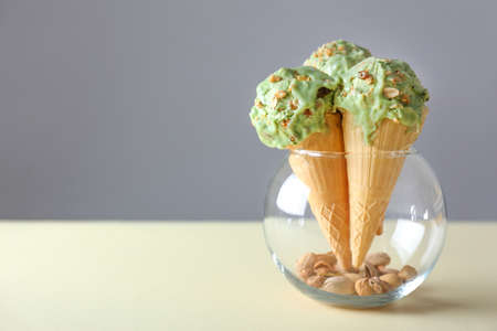 Wafer cones with tasty pistachio ice cream on table
