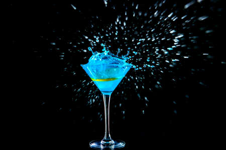 Glass of tasty cocktail with splash on dark backgroundの写真素材