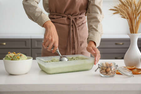 Woman with tasty pistachio ice cream in kitchen, closeupの写真素材
