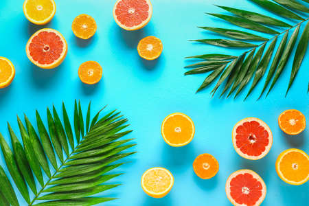 Sweet citrus fruits with tropical leaves on color backgroundの写真素材