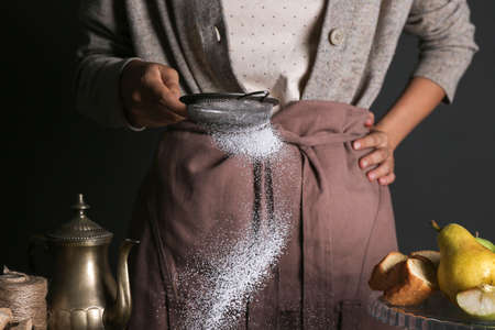 Woman sprinkling sugar powder through sieve, closeupの写真素材