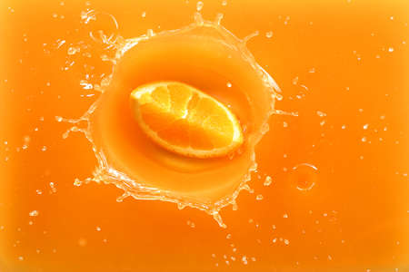Falling of orange piece into juice, top viewの写真素材