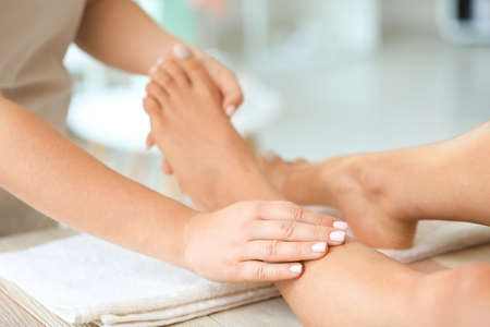 Beautiful young woman receiving foot massage in spa salonの写真素材