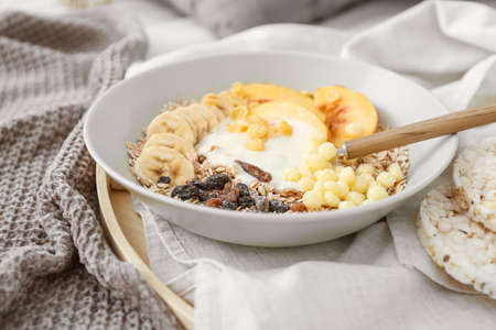 Bowl with tasty fruits, yogurt and granola on trayの写真素材