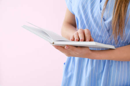 Beautiful young woman with book on color background, closeup