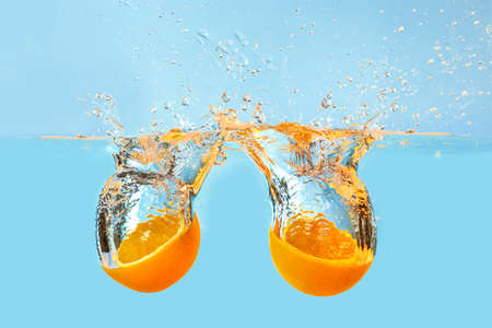 Falling of orange halves into water on light backgroundの写真素材