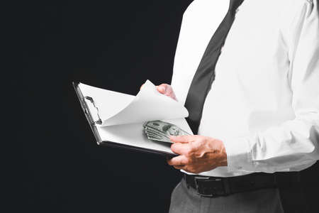 Businessman with bribe against dark background. Concept of corruption
