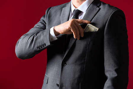 Businessman putting bribe in pocket against color background. Concept of corruptionの写真素材