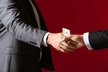 Businessman taking bribe against color backgroundの写真素材