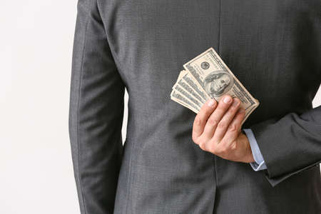 Businessman with bribe against light background, closeup
