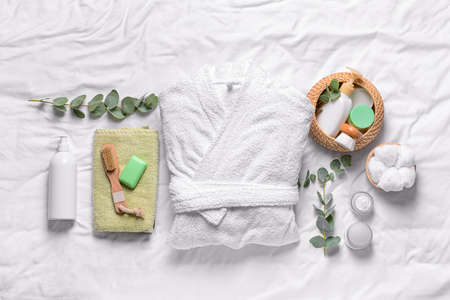 Clean bathrobe with spa supplies on white backgroundの写真素材
