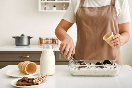 Woman preparing tasty ice cream in kitchen