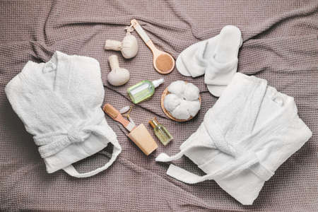 Clean bathrobes with spa supplies on plaid