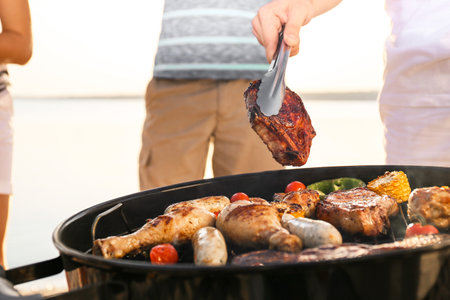 Man cooking tasty meat on barbecue grill outdoors, closeupの写真素材