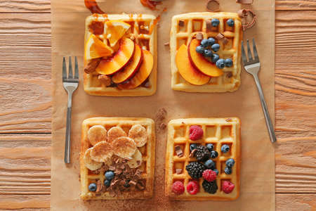 Tasty waffles with fruits and berries on wooden background