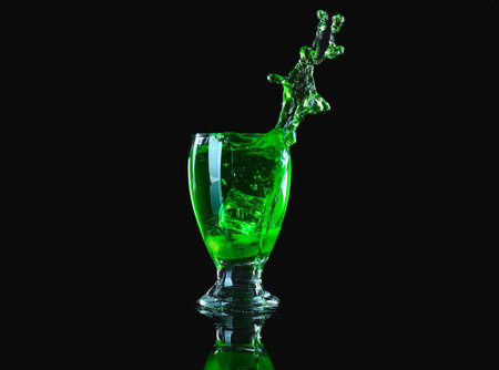 Glass of tasty cocktail with splashes on dark backgroundの写真素材