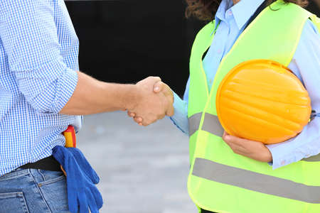 Architect and builder shaking hands in building area