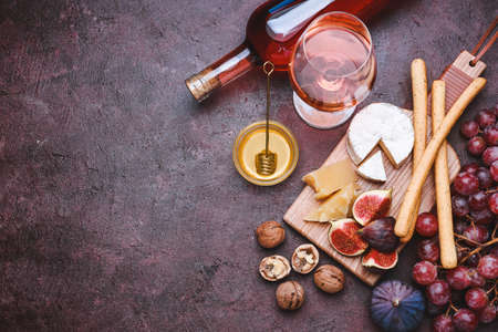 Glass and bottle of tasty wine with snacks on color backgroundの写真素材