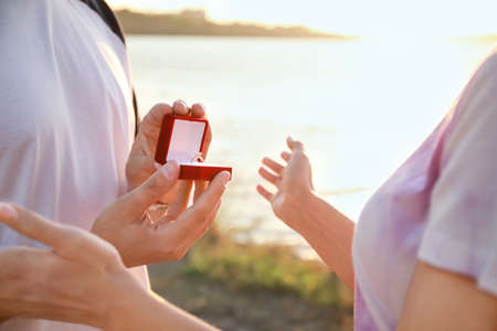 Young man proposing to his beloved near river, closeupの写真素材
