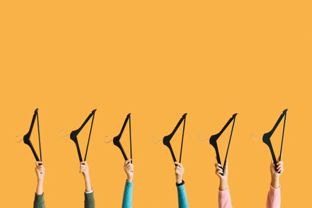 Female hands with clothes hangers on color backgroundの写真素材