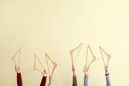 Female hands with clothes hangers on light backgroundの写真素材