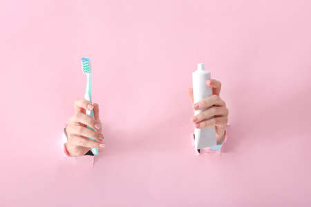 Female hands with toothbrush and paste on color backgroundの写真素材