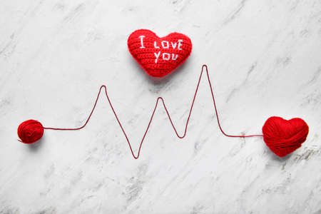 Composition with hearts and cardiogram made of thread on light background