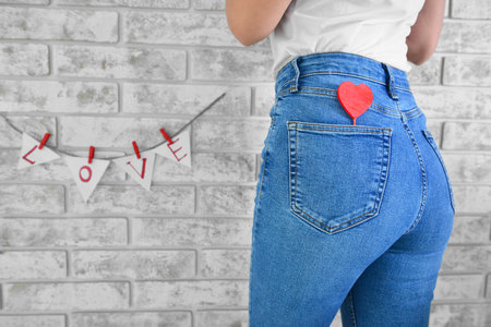 Woman with red heart against brick wall