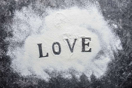 Word LOVE and white flour on grunge backgroundの写真素材