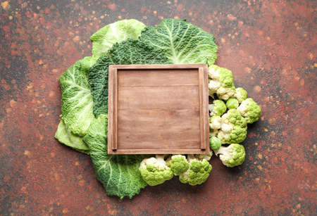 Wooden board with different fresh cabbage on color backgroundの写真素材