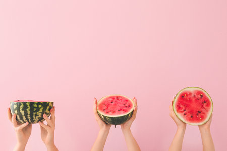 Female hands with halves of ripe watermelon on color backgroundの写真素材