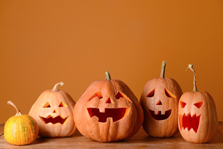 Halloween pumpkins on wooden table against color backgroundの写真素材