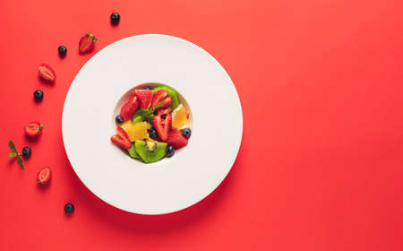 Plate with tasty fruit salad on color background