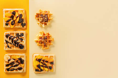 Sweet tasty waffles with chocolate and fruits on color backgroundの写真素材