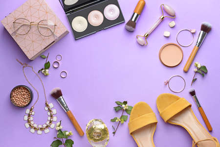 Frame made of decorative cosmetics and female accessories on color background