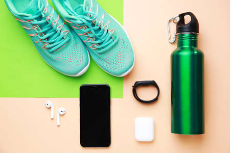 Sports water bottle, shoes, mobile phone and gadgets on color backgroundの写真素材
