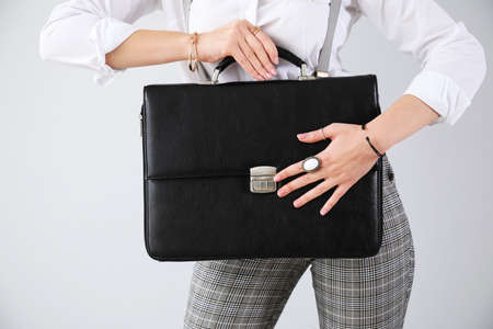 Fashionable young woman with briefcase on light backgroundの写真素材