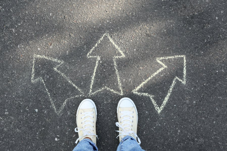 Person standing on road with arrows pointing in different directions. Concept of choice